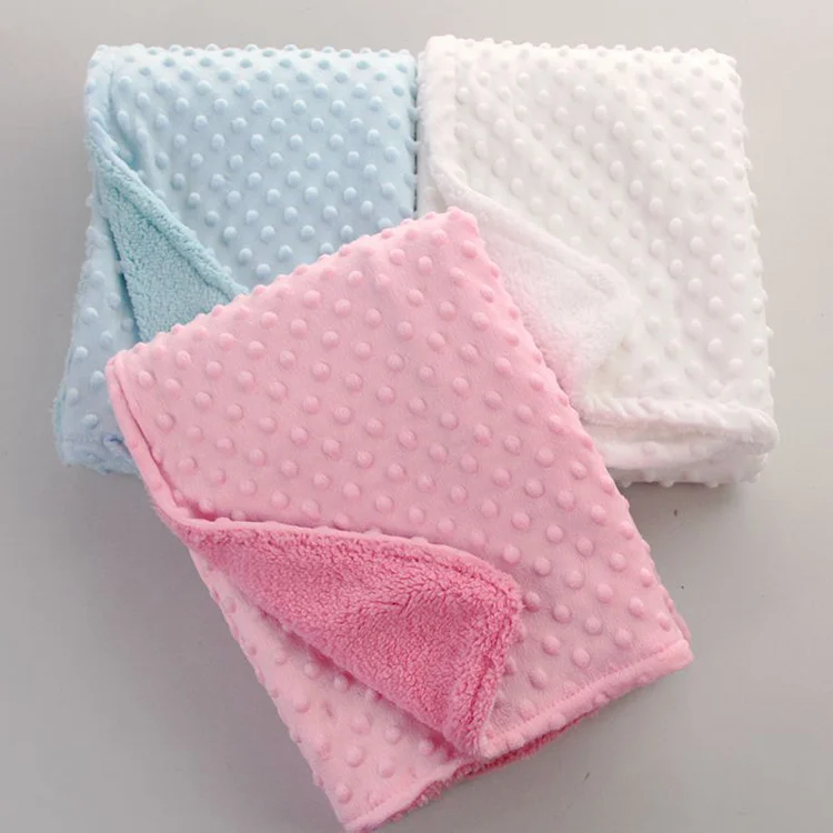 Orange newborn receiving blanket with soft fluff, displayed on a baby's crib