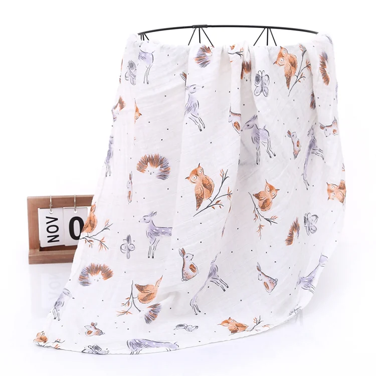 Green floral muslin swaddle blanket placed on a changing table