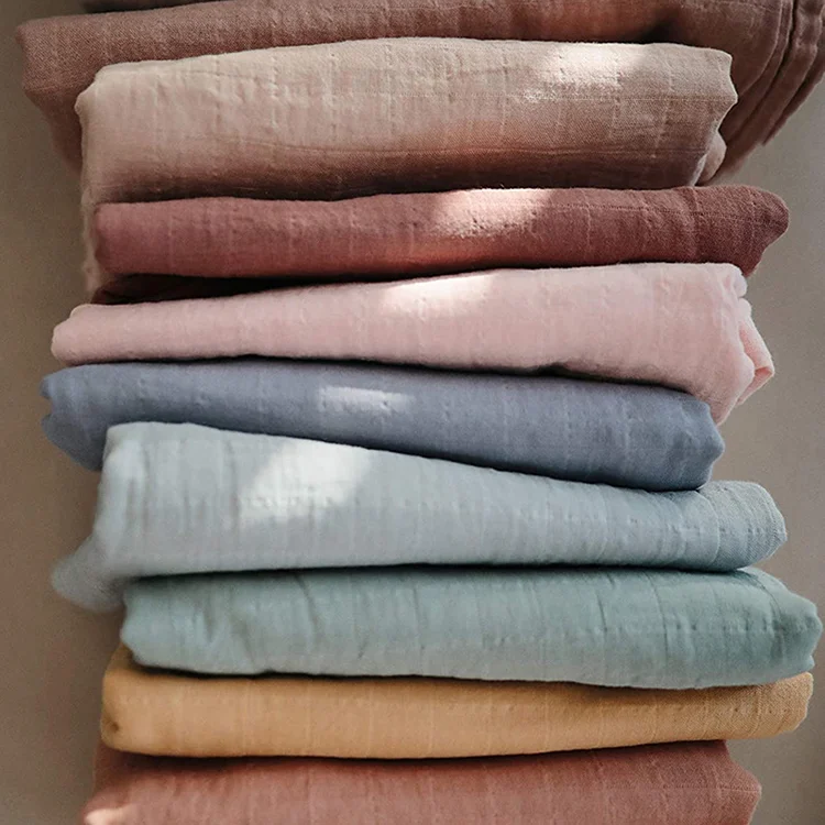 Green 47x47 inch cotton bamboo muslin swaddle blanket folded with headbands visible