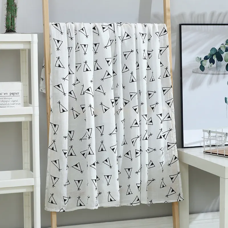 Green leaves-patterned muslin swaddle blanket folded in a triangle