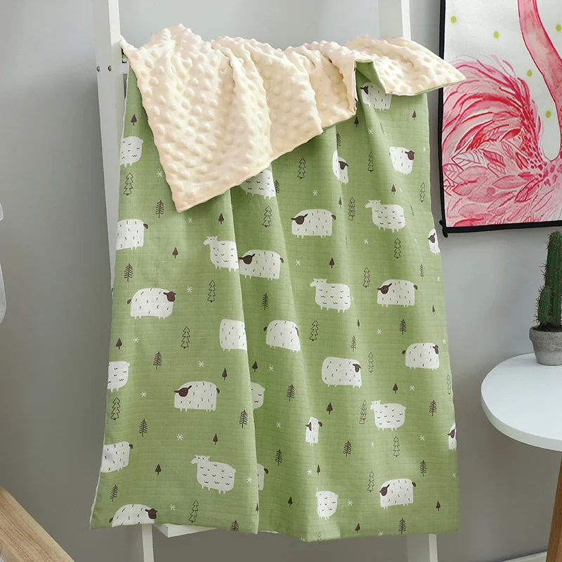 Red baby blanket with dot and plant design, shown on a baby bed