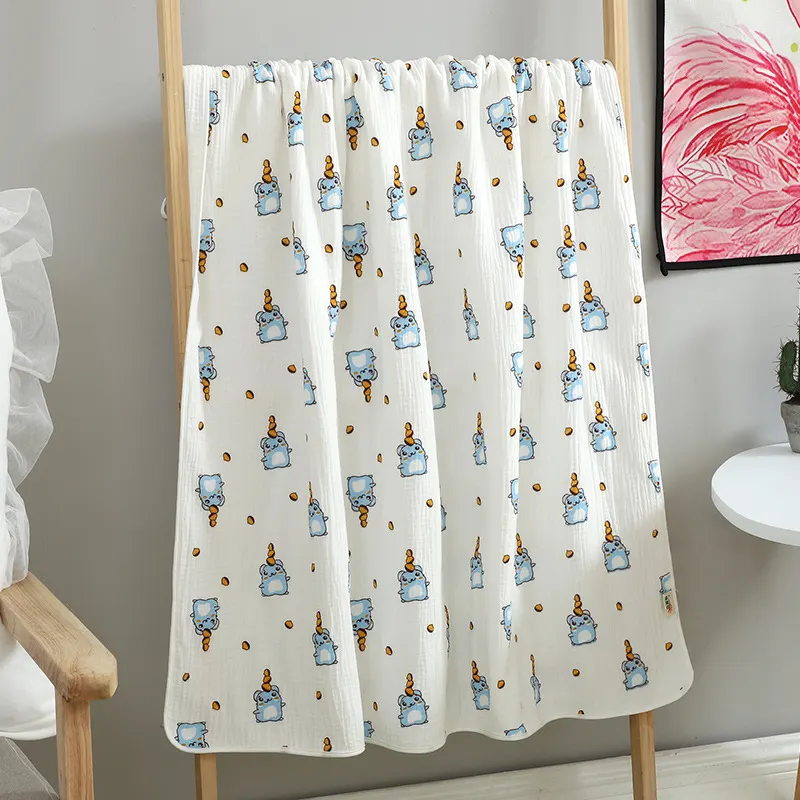 Blue animal-patterned cotton muslin blanket spread out on a white surface