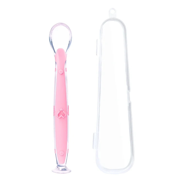 Blue silicone feeding spoon with suction cup attached to a smooth table surface