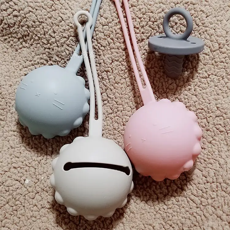 Pink silicone pacifier holder with strap attached to a stroller