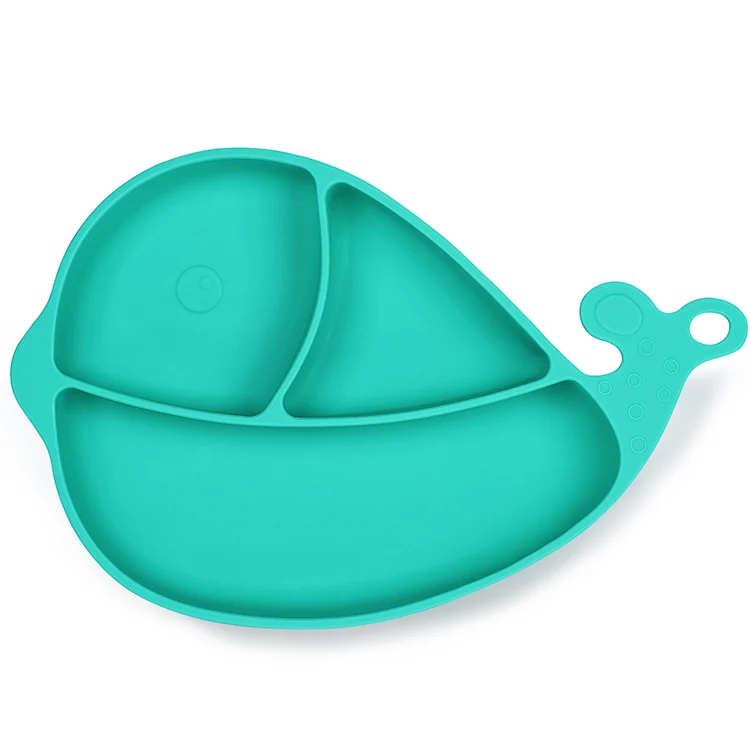 Whale-shaped silicone suction plate in blue, standing on a high chair tray