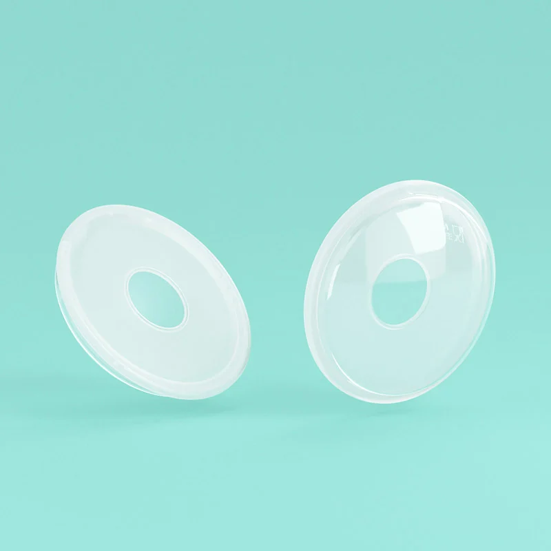 Two soft silicone breast milk collectors placed side by side, white box packaging visible
