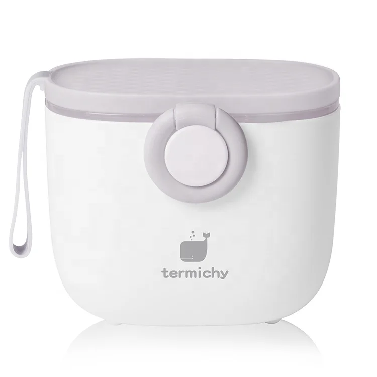 Green milk powder dispenser with lid removed, showing the separate scoop compartment