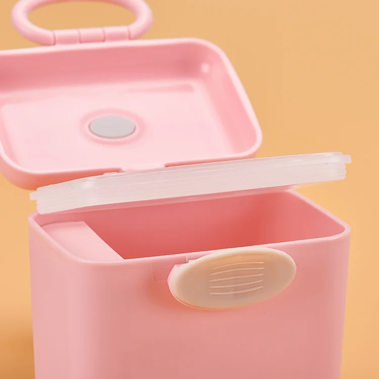 Formula dispenser with scoop and lid in hand, showing the child-lock mechanism