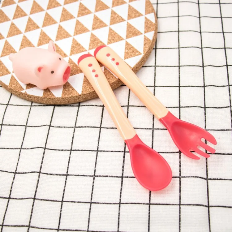 Green baby spoon and fork set with soft TPE tips, close-up of the heat-sensitive tip