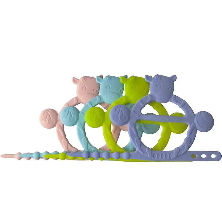 Cow-shaped teething bracelet in pink, with gift box open and product inside