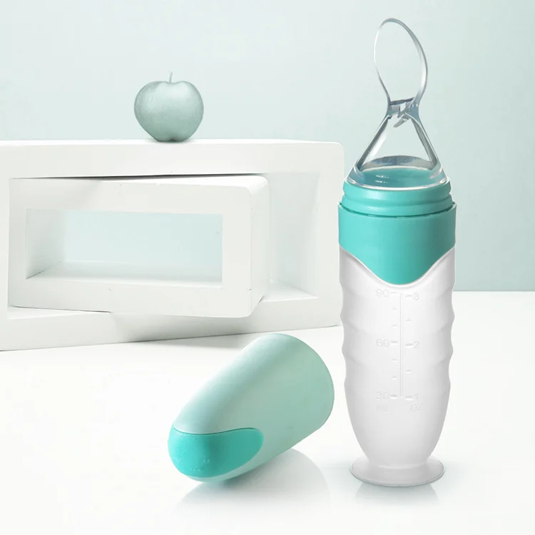 Pink and green silicone squeeze spoon food feeder with suction cup base