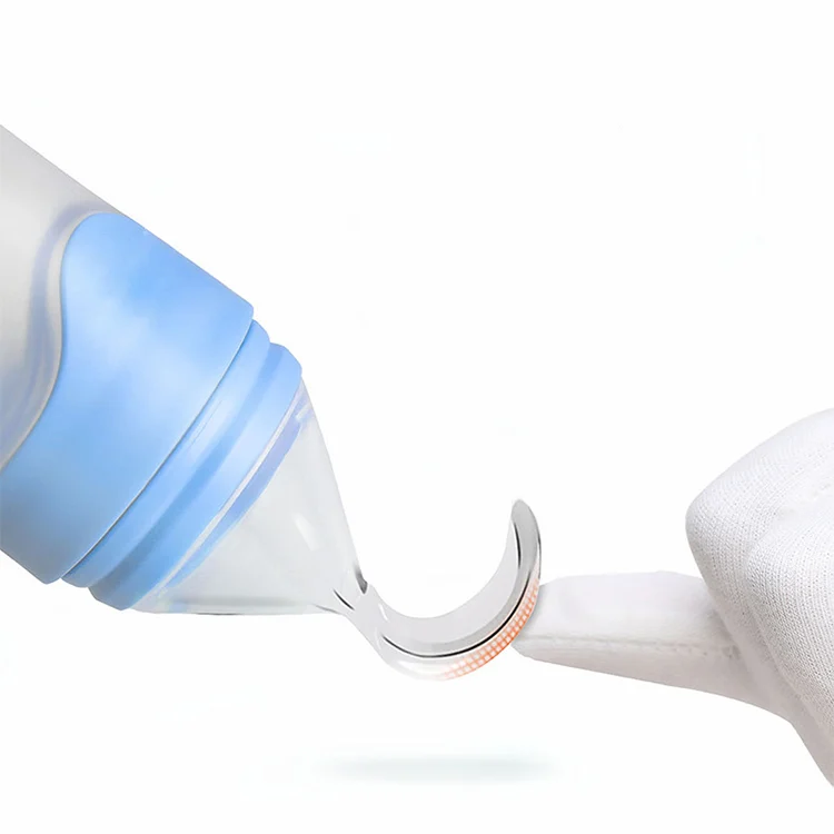 Feeding bottle in use, squeezed to dispense food into a baby's mouth