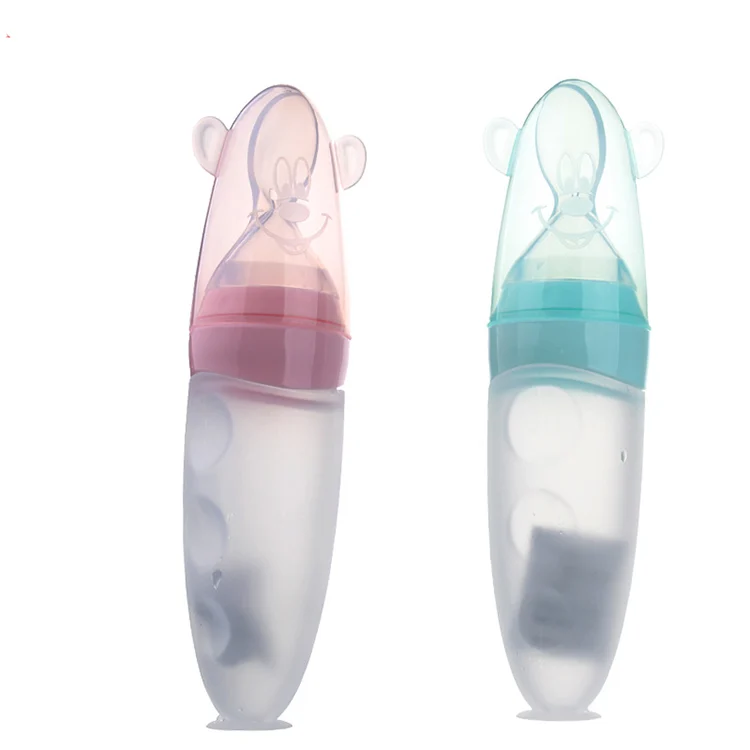 Silicone squeeze food dispenser bottle with suction base, filled with pureed food, standing on a table