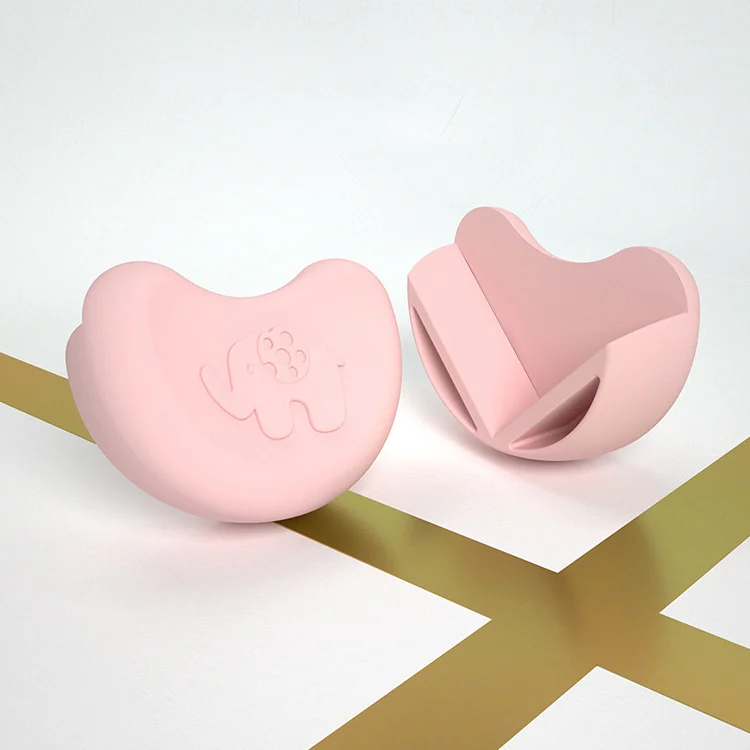 Two pink elephant-shaped silicone corner protectors on a wooden table corner