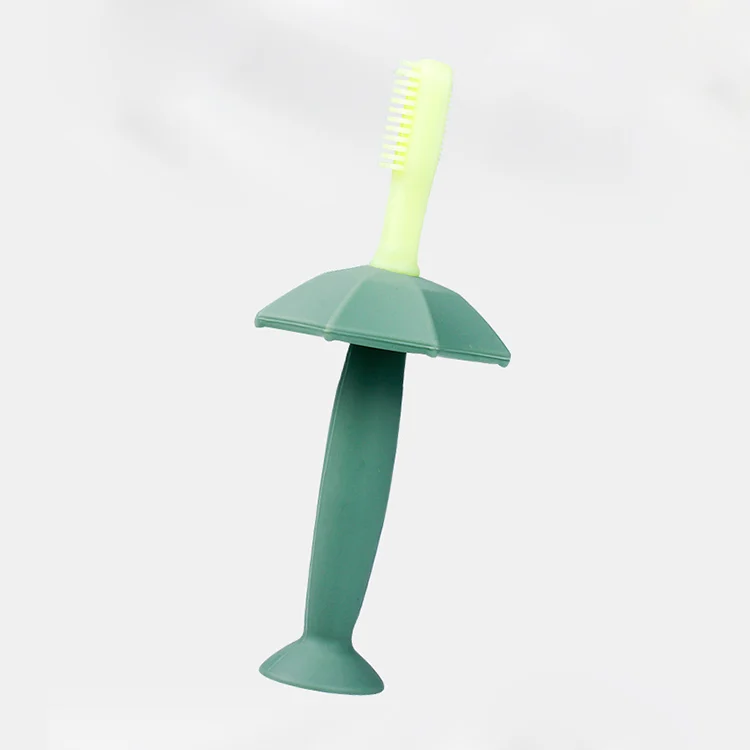 Pink silicone baby toothbrush with pig handle and safety cap, standing upright on a flat surface