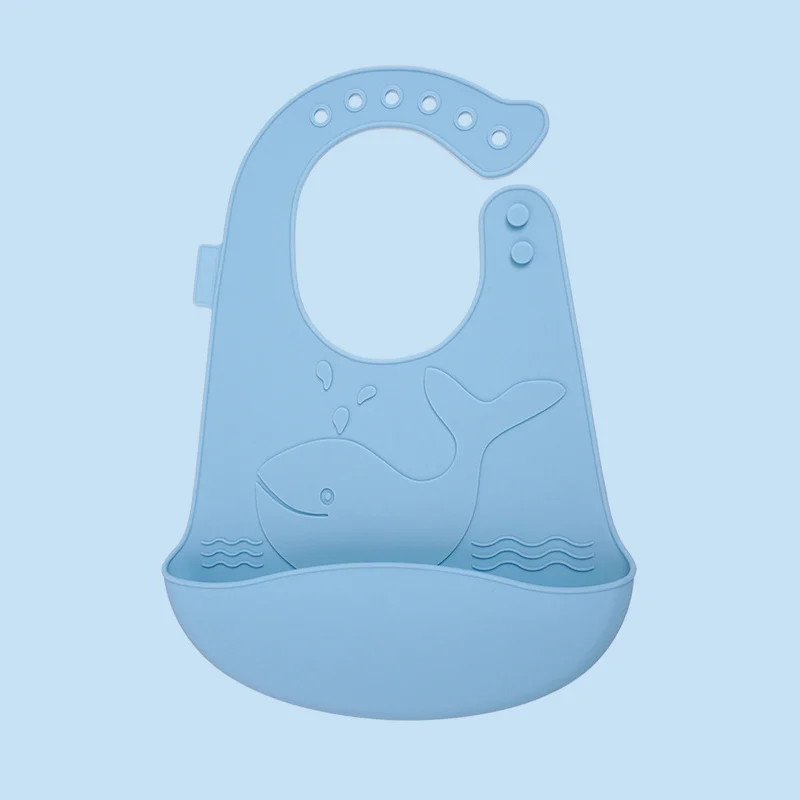 Whale-shaped adjustable silicone bucket bib in white, worn by a toddler
