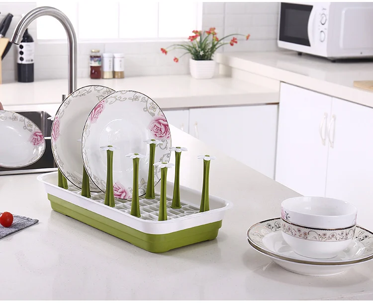 Baby bottle drying rack with bottles, cups, and spoons arranged on the surface