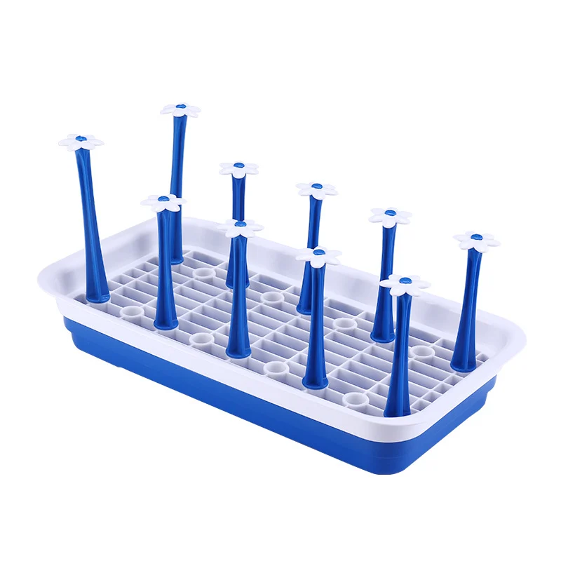 Green baby bottle drying rack with bottles and cups drying on the surface