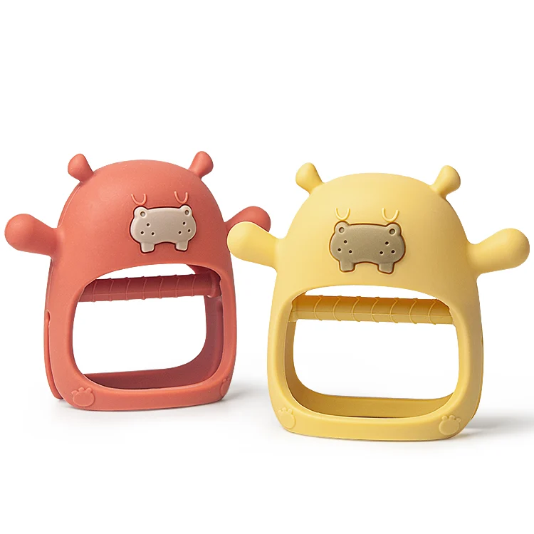 Pink hippo-shaped wearable teether with wrist strap, worn on a baby's hand
