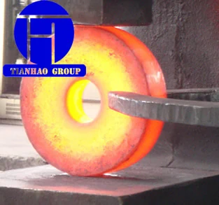 Glowing hot forged steel ring being handled at the forging press
