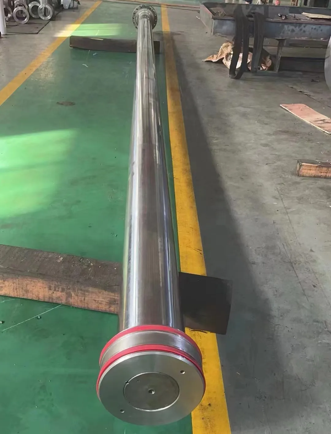 Long machined forged steel roll shaft on the Tianhao workshop floor