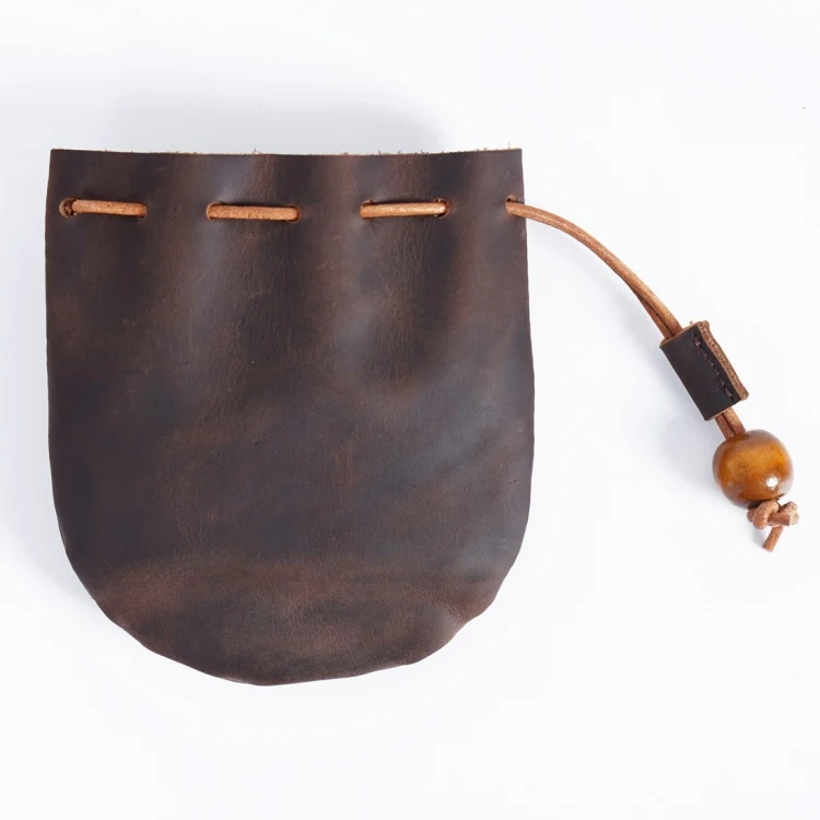 Leather pouch holding coffee beans on a wooden surface