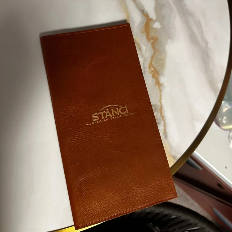 Leather order book shown with bills and a pen