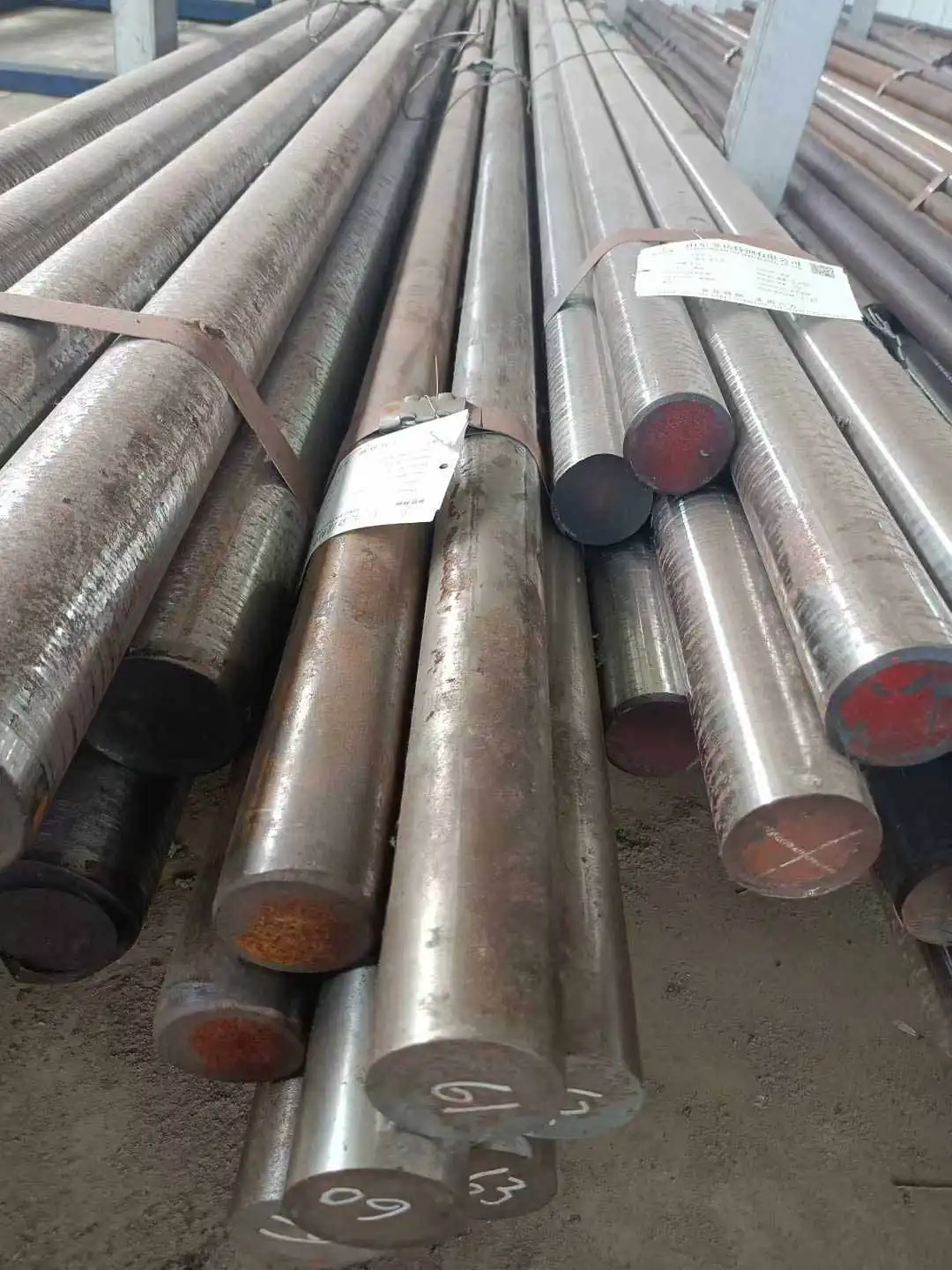 stacked large diameter round steel bars with paper tags