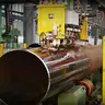 Large rusted steel cylinder on rollers in a machining workshop