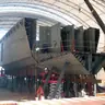 Barge hull under construction on blocks inside a shipyard shed