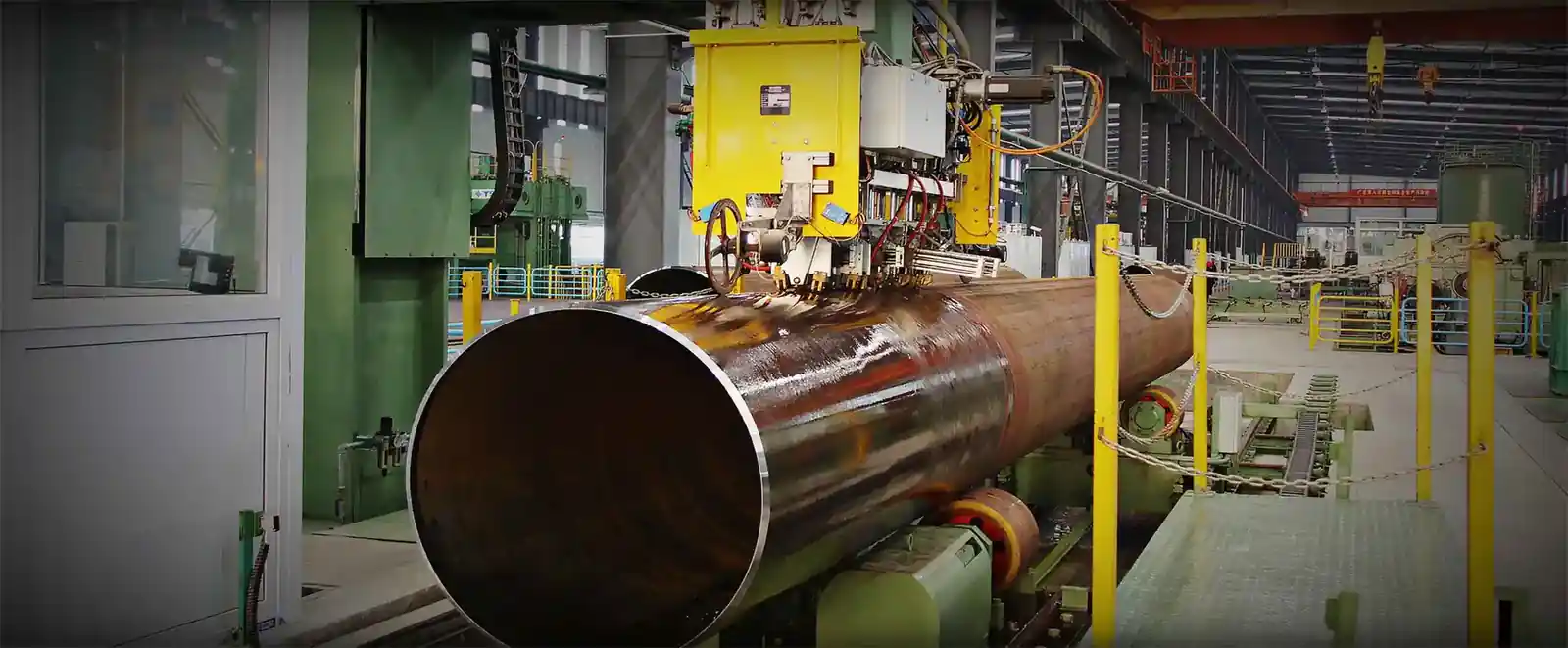 Large rusted steel cylinder on rollers in a machining workshop