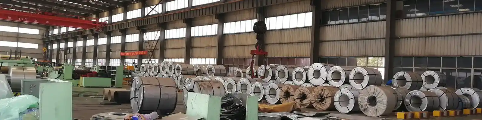 Rows of steel coils standing on stands in a mill warehouse