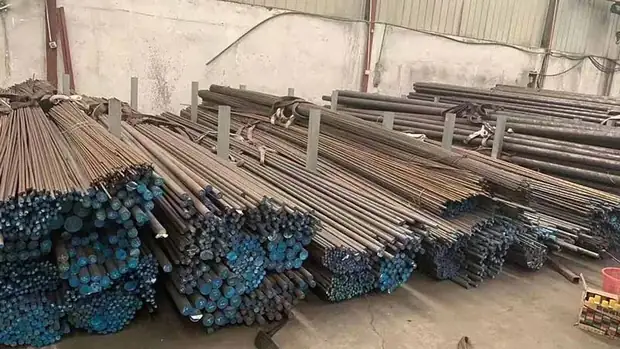 bundles of steel pipes and bars stacked along a warehouse wall