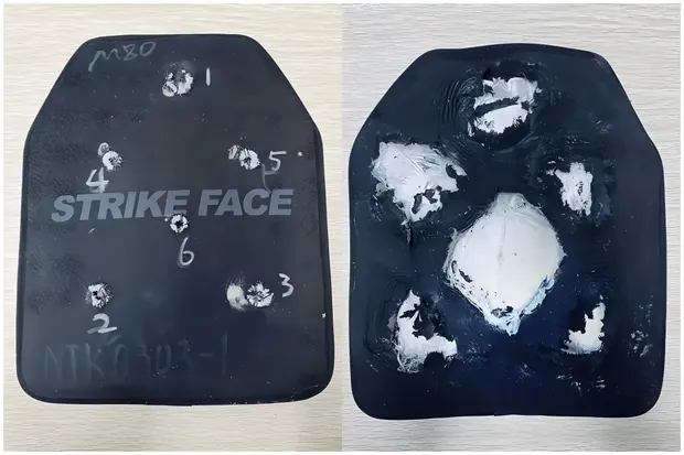 two tested armor panels with handwritten markings and bullet strikes