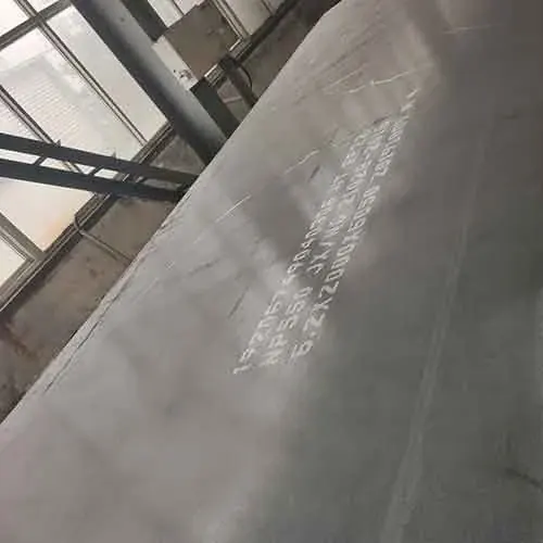 large gray steel plate leaning inside a daylit workshop