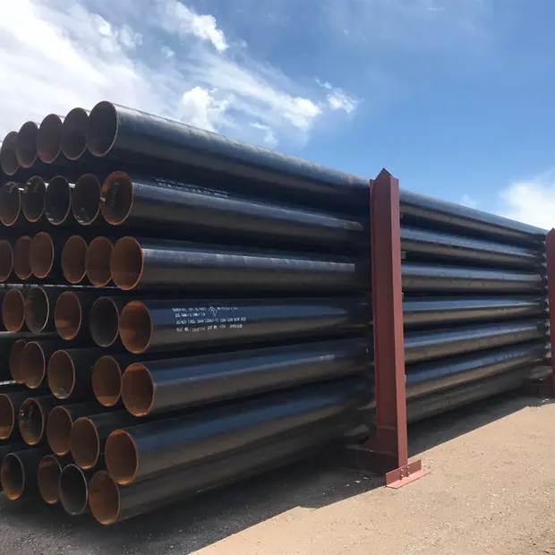Black coated steel line pipes stacked outdoors under blue sky