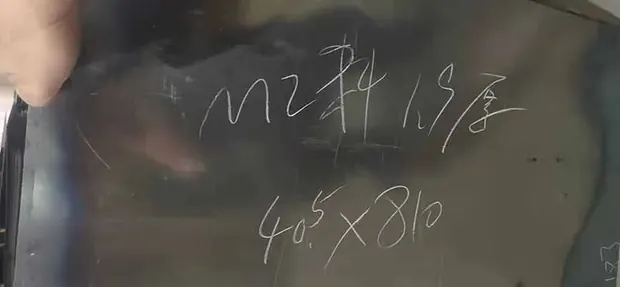 Dark steel plate surface with handwritten chalk size markings