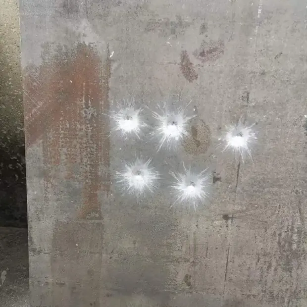 Steel plate surface marked by five bullet impact craters