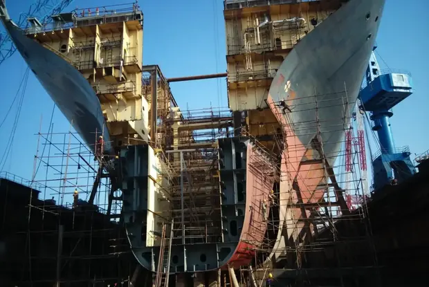 Ship hulls under construction with scaffolding in a shipyard
