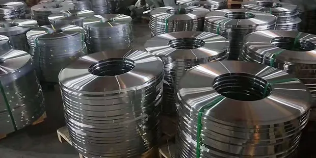 Rows of stainless strip coils banded with green straps on pallets