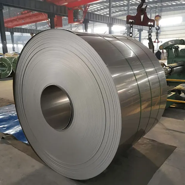 Large stainless steel coil standing on a workshop floor beneath a crane