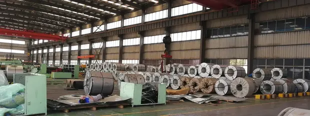Wide view of steel coils lined up along a warehouse bay