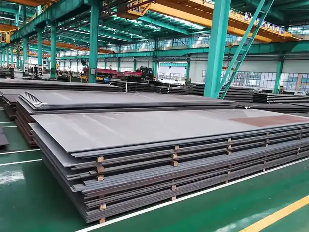 Stacked steel plates on green floor under green roof trusses