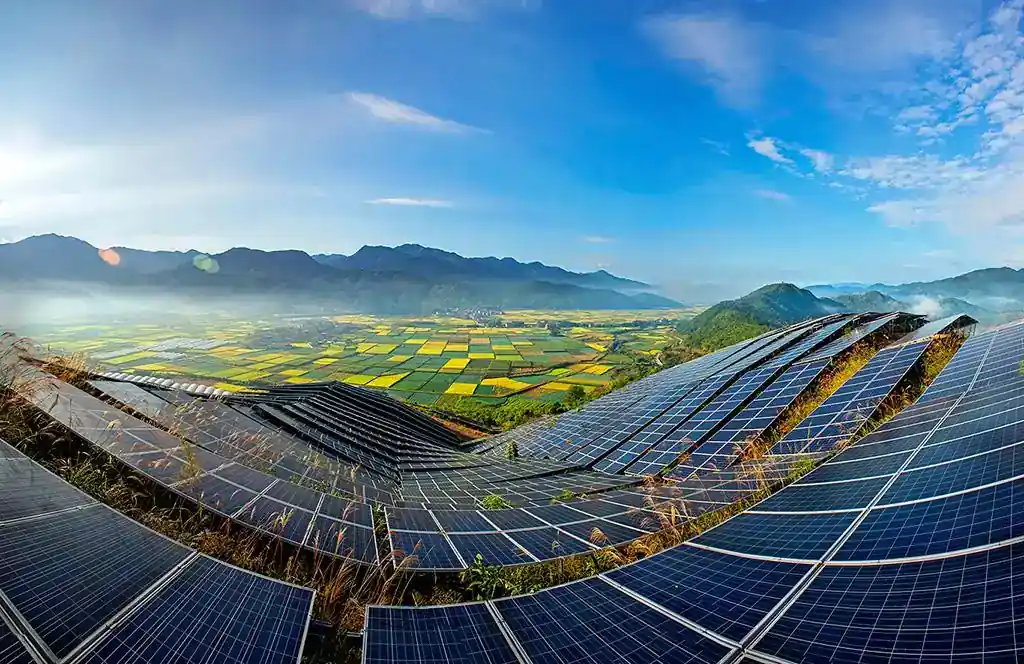 Hillside solar power plant with long rows of PV modules above farmland