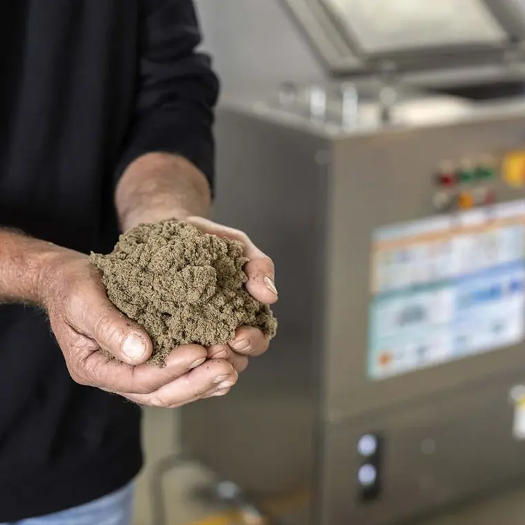 Operator holding finished compost harvested from a TMK composting machine