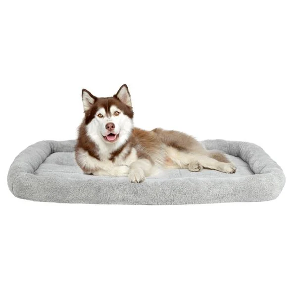 Husky dog lying on a large gray plush bolster pet bed mat against a plain white background
