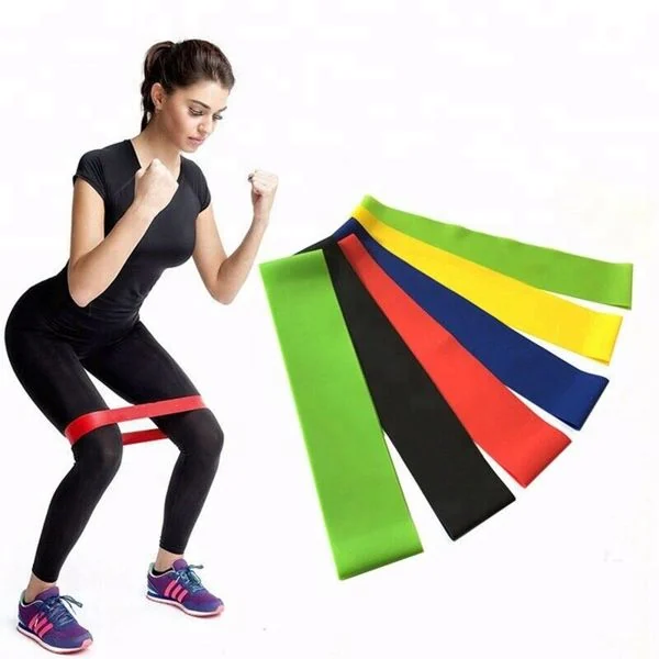 Woman in black sportswear squatting with red resistance band around thighs, beside
