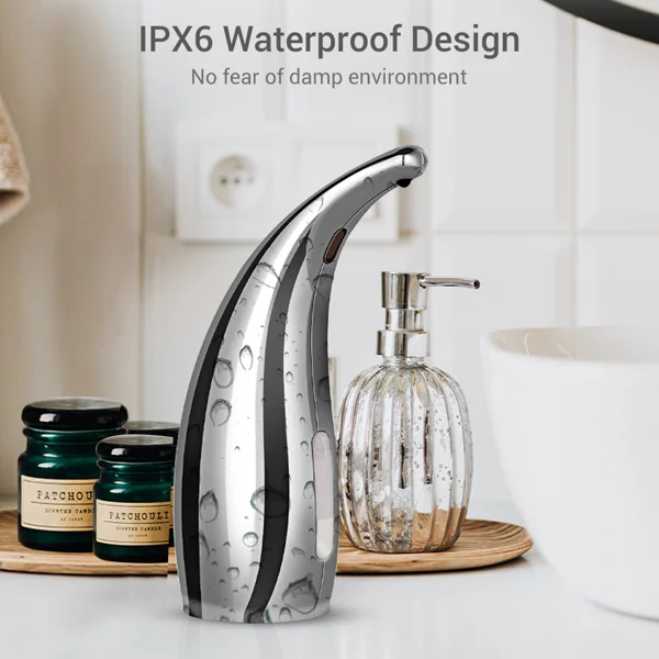 Chrome curved automatic soap dispenser with water droplets on a bathroom counter next to a glass soap bottle.