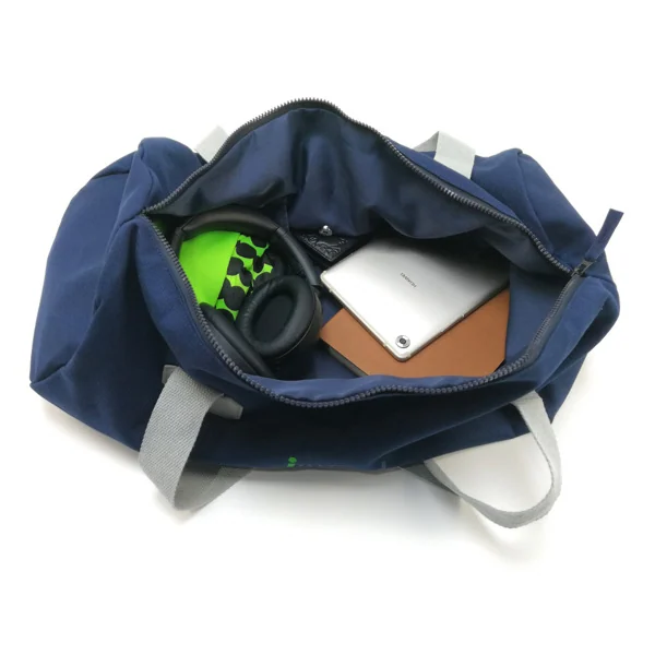Open navy duffel bag showing contents including headphones, tablet, and notebook