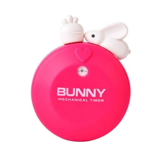 Pink round mechanical kitchen timer with white cartoon rabbit figure on top and BUNNY branding on its face